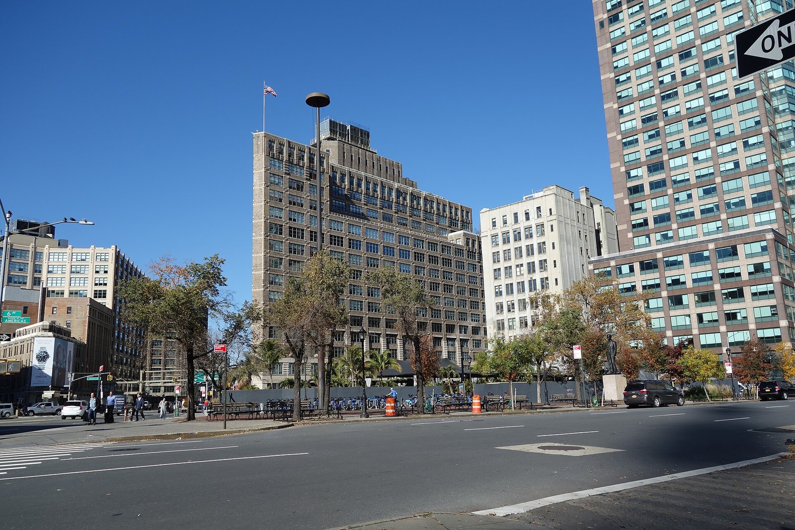 A city plaza with trees and benches in front of One Hudson Square in Manhattan's Hudson Square/SoHo area
