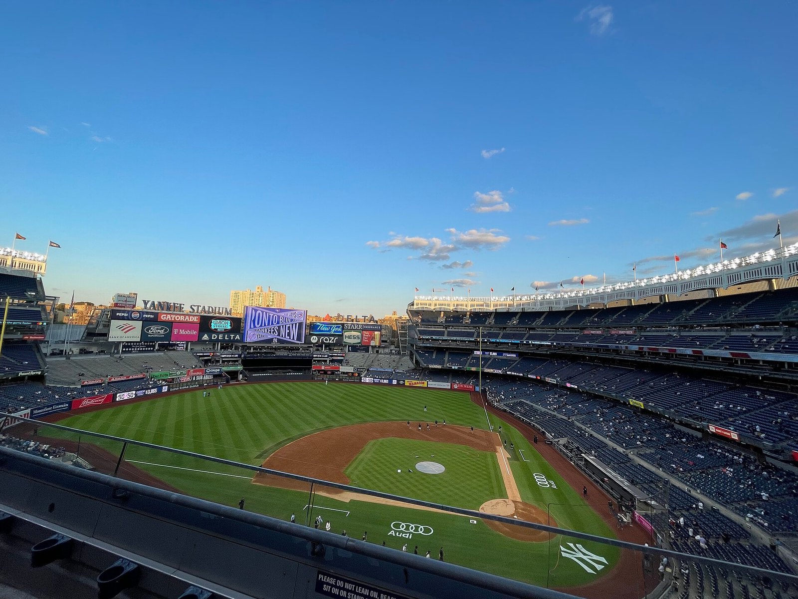 Wide view of Yankee Stadium's playing field and stands under a blue sky at dusk
