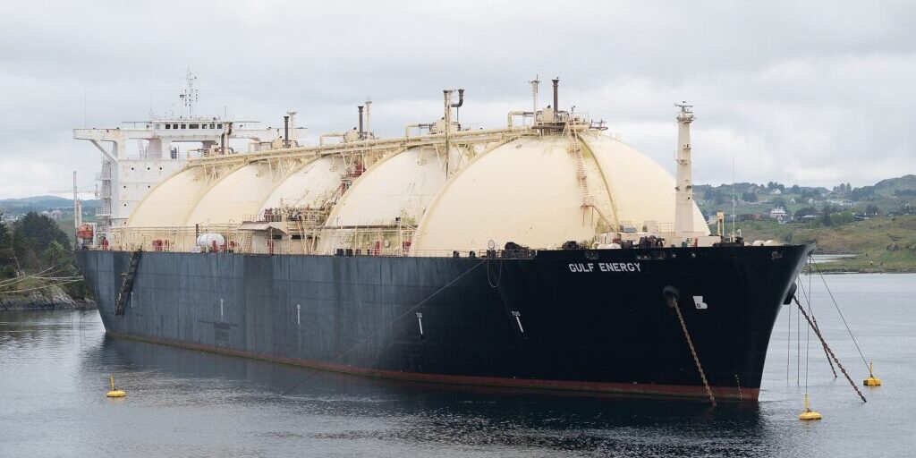 LNG tanker Gulf Energy anchored in a strait near a coastal hillside