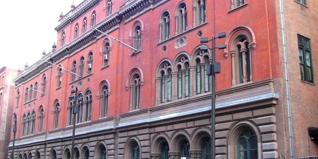 The Public Theater building, a distinctive red brick structure with ornate architectural detailing at 425 Lafayette Street