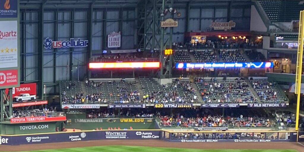Fans fill the right field seating at American Family Field, with the pitch clock glowing at center