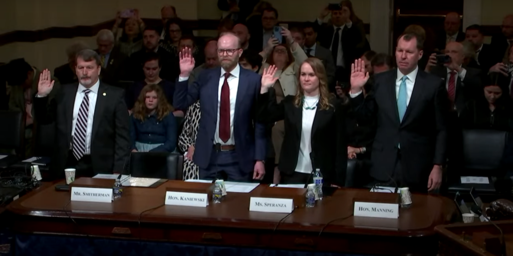 Witnesses raising their hands during a congressional hearing to take an oath