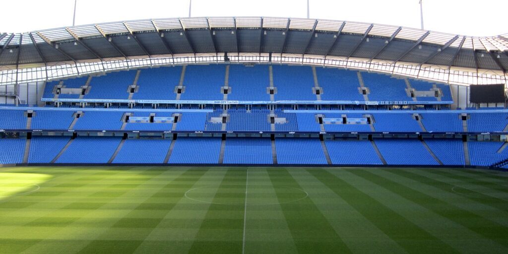 Interior of Etihad Stadium with pitch and blue seating