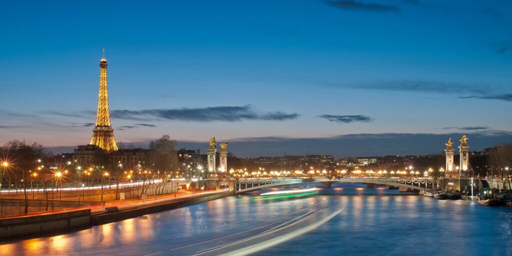 Eiffel Tower and Pont Alexandre III illuminated at night above the Seine