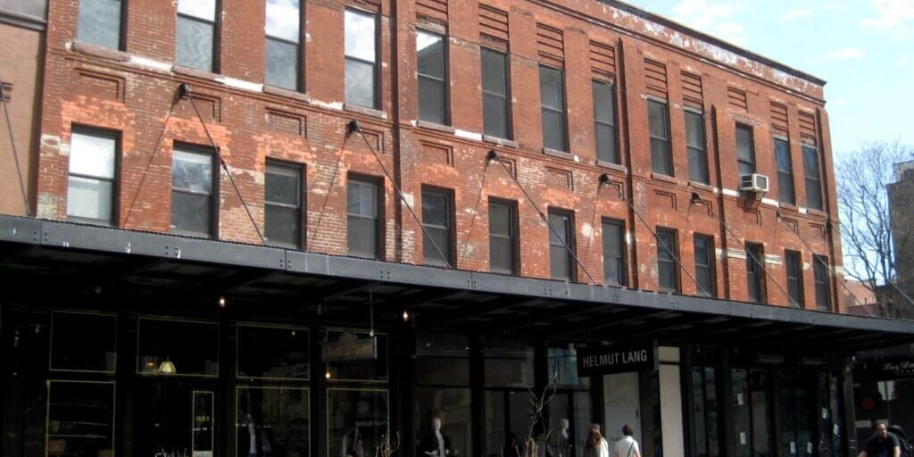 A row of brick storefronts with fashion boutiques and mannequins along a Meatpacking District street