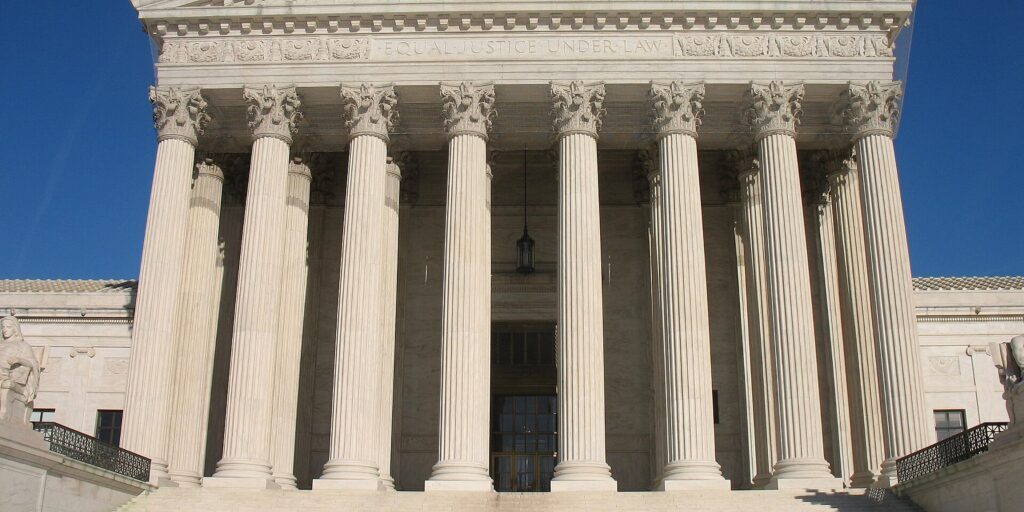 Marble facade of the Supreme Court of the United States in Washington, D.C., with columns and steps under a blue sky.