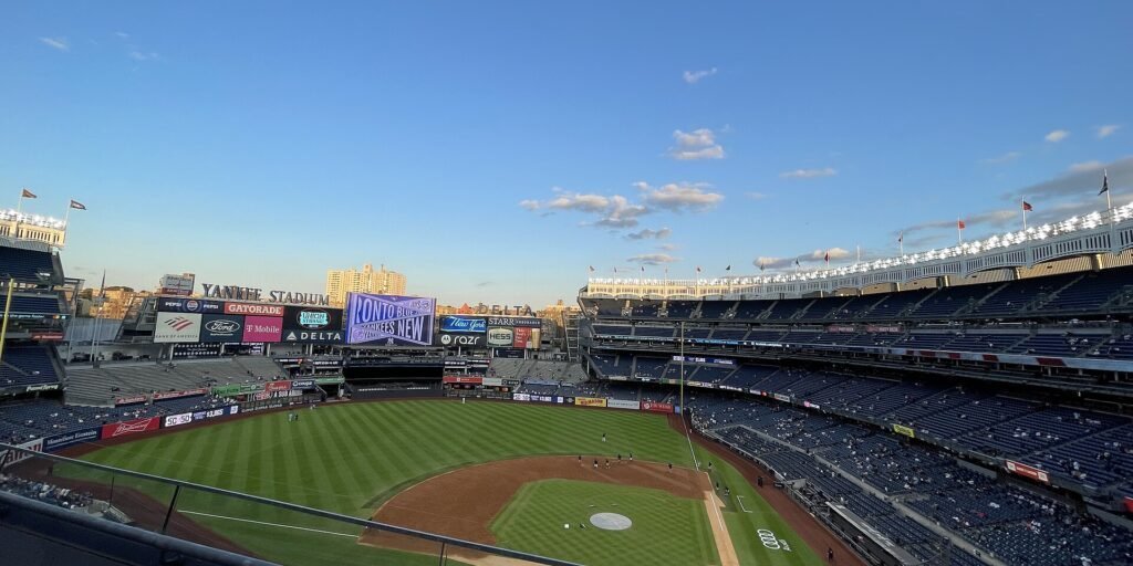 Wide view of Yankee Stadium's playing field and stands under a blue sky at dusk
